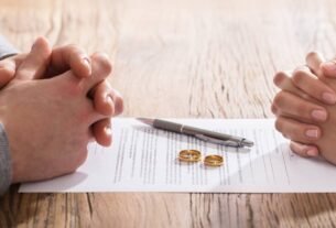 Casal diante de documento de divórcio com alianças sobre contrato, representando divórcio consensual e litigioso no Brasil